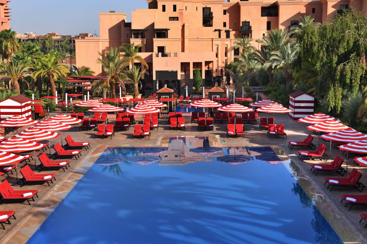 Piscine de l'hôtel avec transats rouges et palmiers