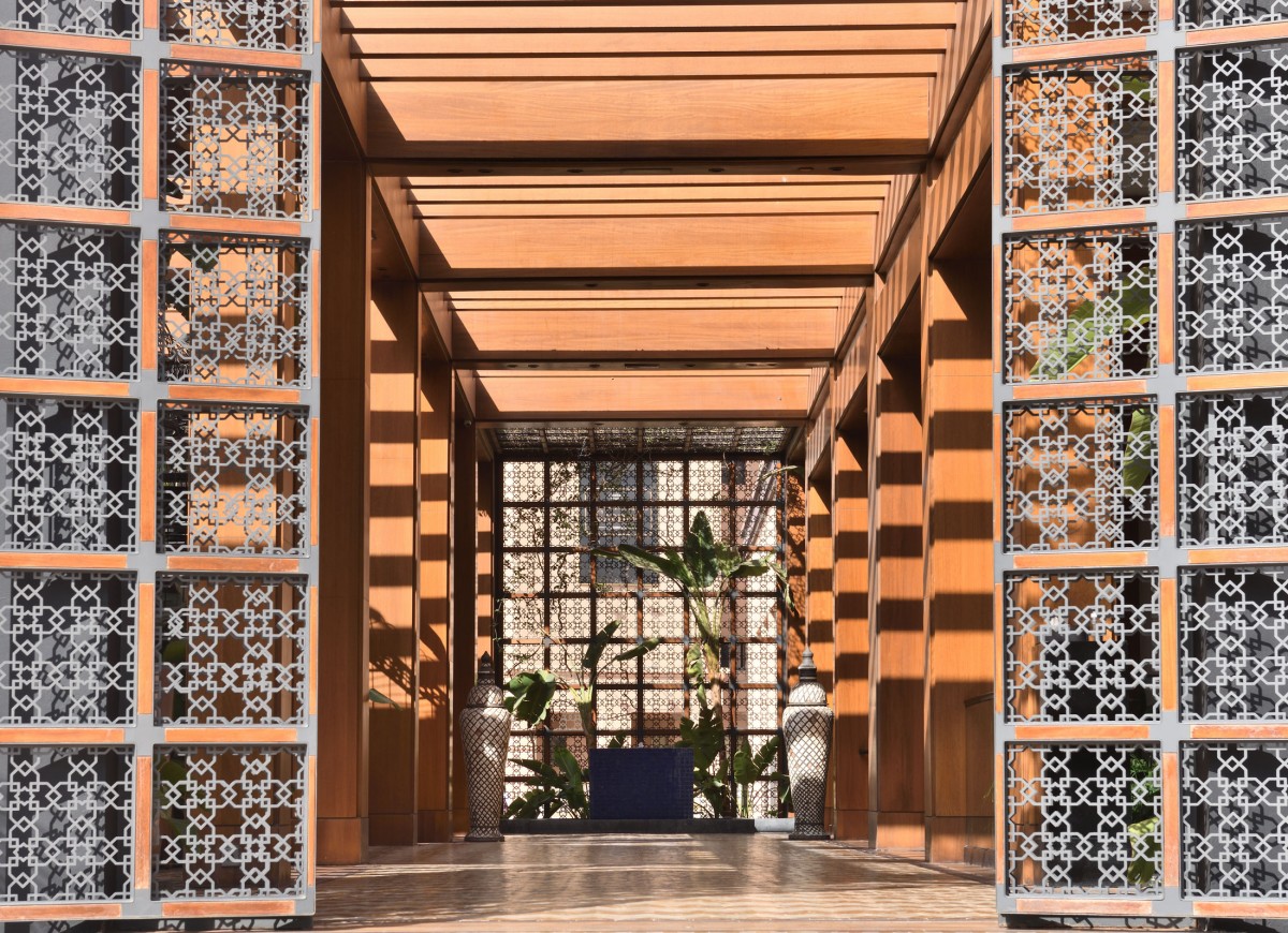 Allée couverte de bois et moucharabieh menant aux jardins de l'hôtel